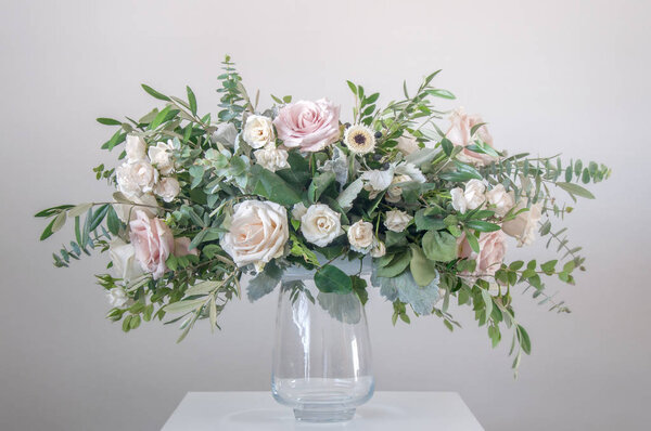 Beautiful bouquet of mixed flowers in a glass vase on gray wall background