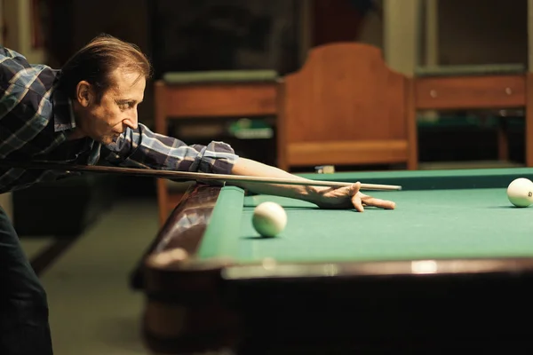 a pool player takes aim at the ball