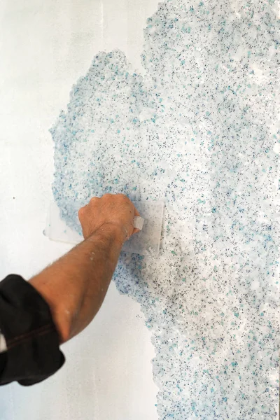 the worker puts liquid Wallpaper on the wall