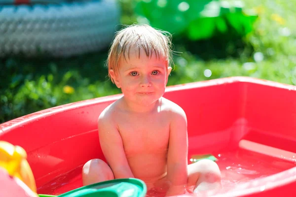 Маленький ребенок плавает на улице в маленьком бассейне — стоковое фото