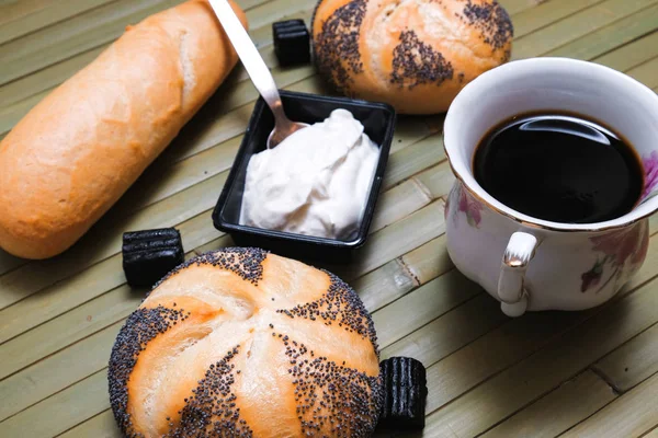 Panecillos con semillas de amapola y una taza de café — Foto de Stock