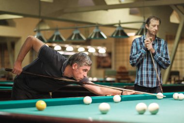 Oyuncu bilardoda topa nişan alıyor.