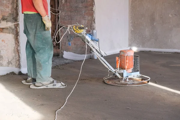 the workers grind the concrete floor at the construction site