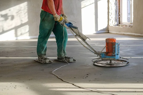 Os trabalhadores moem o piso de concreto no canteiro de obras — Fotografia de Stock