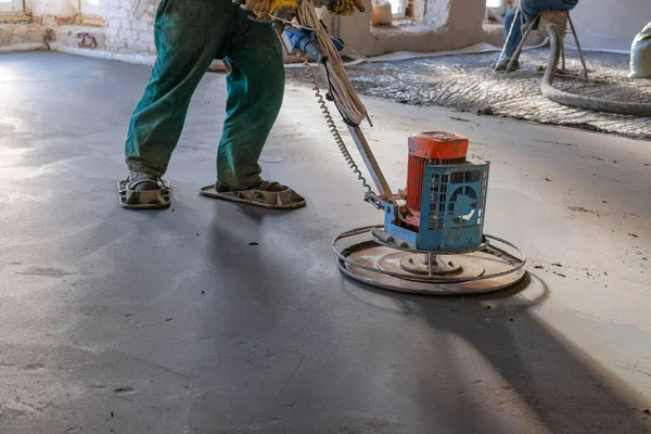 Os trabalhadores moem o piso de concreto no canteiro de obras — Fotografia de Stock