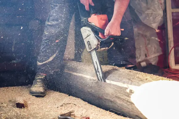 Der Arbeiter sägt mit der Kettensäge einen Baumstamm ab — Stockfoto