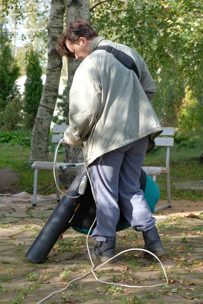 Una donna pulisce le foglie con un aspirapolvere — Foto Stock