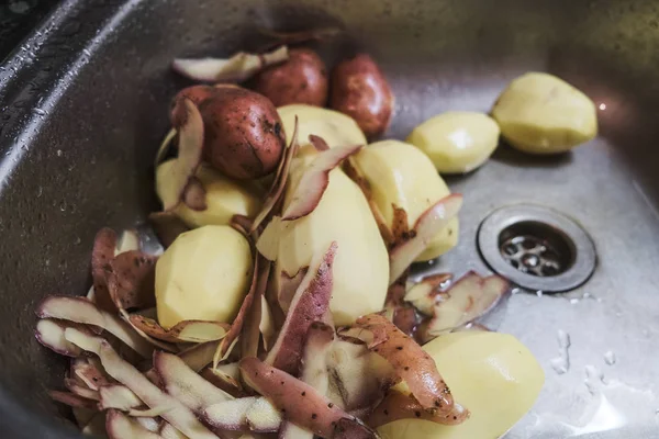 Batatas descascadas cruas deitadas na pia da cozinha — Fotografia de Stock