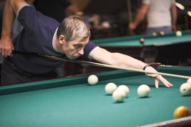 Oyuncu bilardoda topa nişan alıyor.