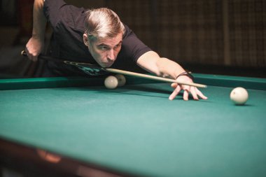 Oyuncu bilardoda topa nişan alıyor.