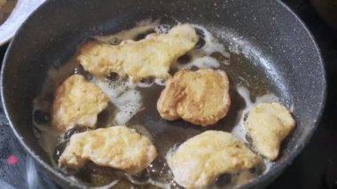Golden chicken legs in batter fried in a pan