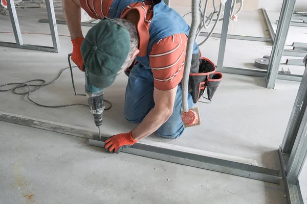 worker screws the screw into the drywall rack