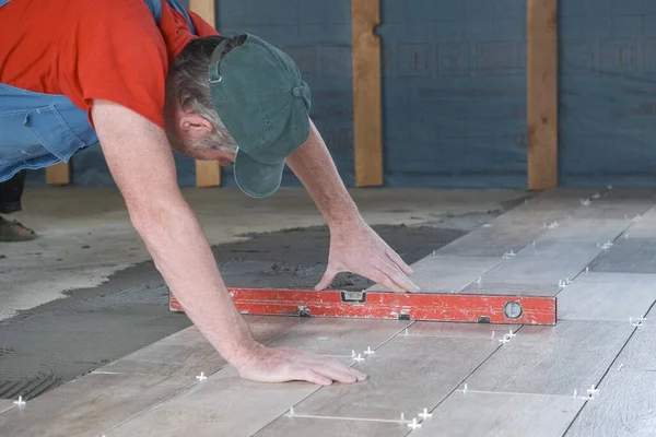 O trabalhador coloca telhas cerâmicas no canteiro de obras — Fotografia de Stock