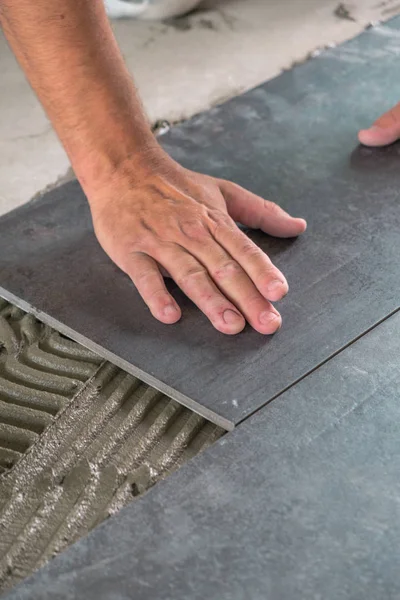 陶磁器の床タイルを接着面に配置する労働者 — ストック写真