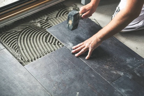 陶磁器の床タイルを接着面に配置する労働者 — ストック写真
