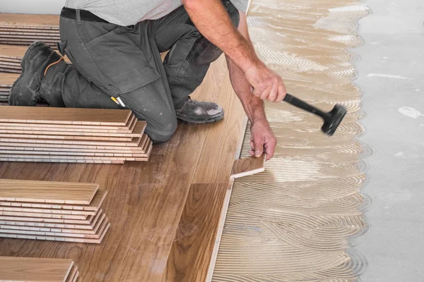 工人在应用胶粘剂上安装木地板板 — 图库照片