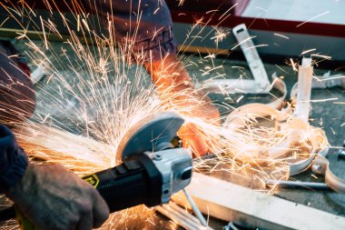 Demirleri öğütücüyle kesen bir işçi.