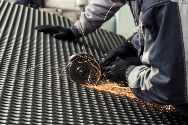 Worker cutting the steel mesh with the grinder in the workshop