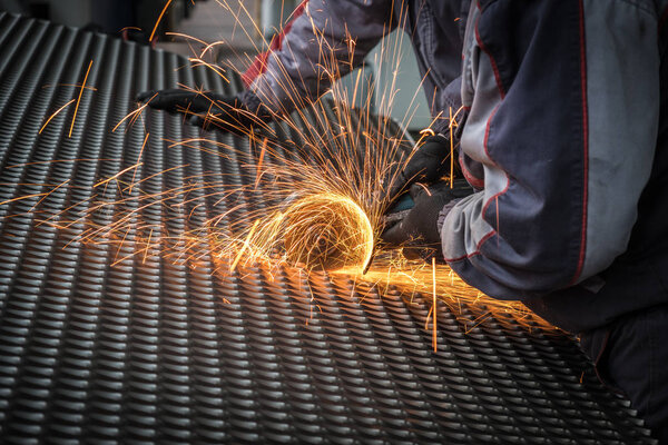 Worker cutting the steel mesh with the grinder in the workshop