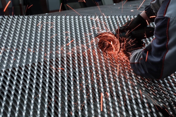 Worker cutting the steel mesh with the grinder in the workshop