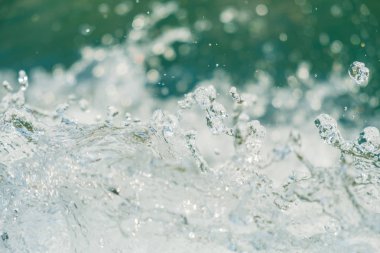 Arkaplanda turkuaz nehir yüzeyi olan temiz su damlaları havada yakalanır.