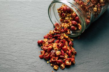 Yaban gülü kuru meyvesi cam kavanozdan siyah kaya yüzeyine döküldü.