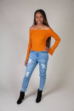 Studio shot of a young Black woman with vintage orange top and baggy jeans posing on a white background clipart