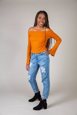 Studio shot of a young Black woman with vintage orange top and baggy jeans posing on a white background clipart