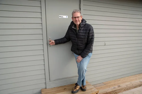 Orta yaş adam çok kötü işemek zorunda mens oda kapının yanında ayakta. Mens sağlık bilinci kavramı.