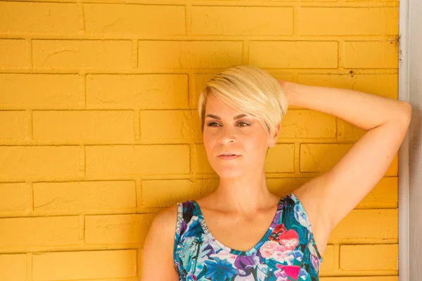 Etty Femme blonde sur mur de briques jaunes — Photo