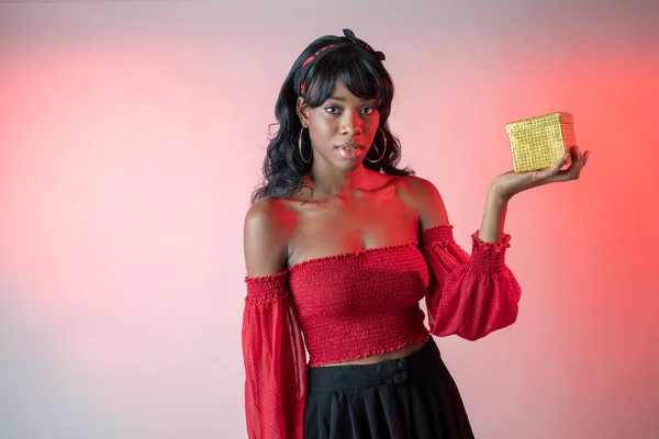 African American woman in red top and black skirt holding gift — Stock Photo, Image