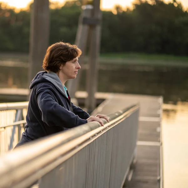 Oudere vrouw die zich uitstrekt in de vroege ochtend door een rivier — Stockfoto