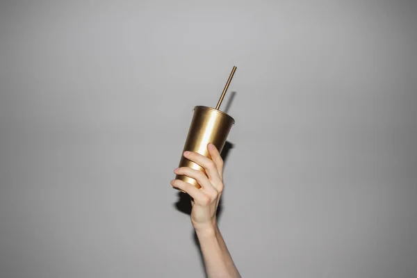 Mano sosteniendo la taza de soda dorada — Foto de Stock