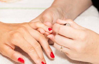 Bir kadının ellerine oje sürüyorum.