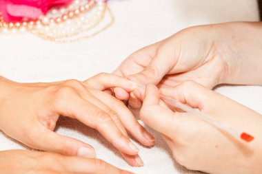 Manikür çivi oje uygulamadan önce bir kadının elinden