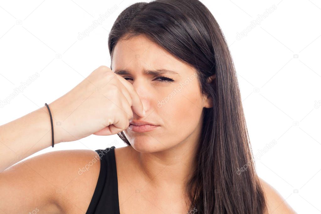 portrait of a brunette woman pinching her nose because of a bad smell