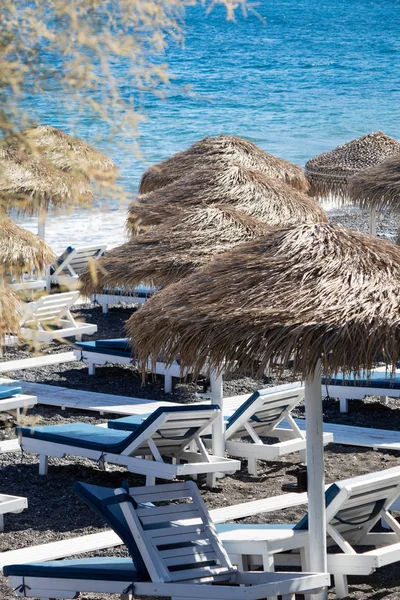 Strand mit Sonnenschirmen und Liegestühlen am Meer in Santorini — Stockfoto