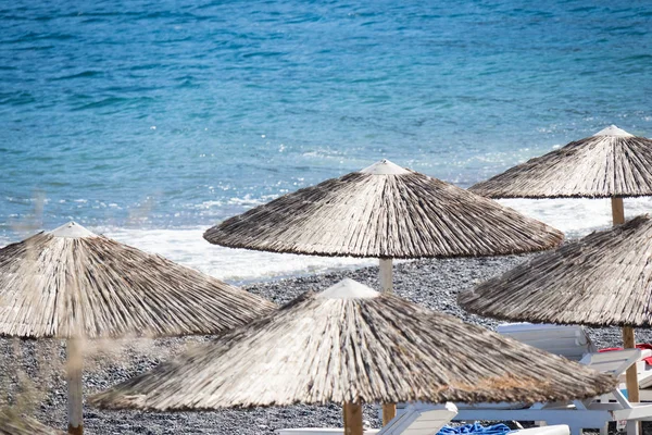 Strand mit Sonnenschirmen und Liegestühlen am Meer in Santorini — Stockfoto