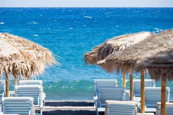 Strand mit Sonnenschirmen und Liegestühlen am Meer in Santorini — Stockfoto