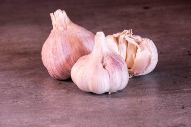 Mutfak tezgahında üç büyük baş pembe sarımsak.