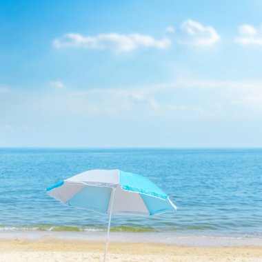Deniz kıyısında bulutlu mavi gökyüzünün altında şemsiye. yumuşak odak