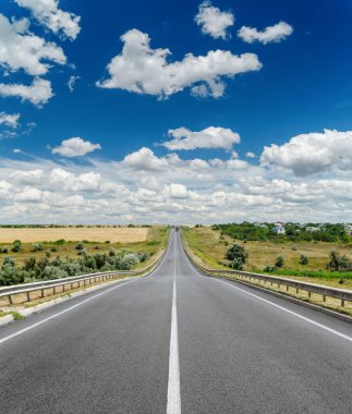 Derin mavi gökyüzünün altında bulutlu beyaz merkezi çizgili yol