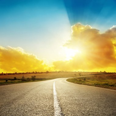 Asfalt yolda parlak turuncu gün batımı