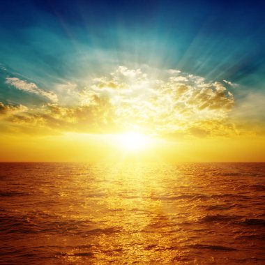 Günbatımında turuncu deniz ve üzerinde bulutlar