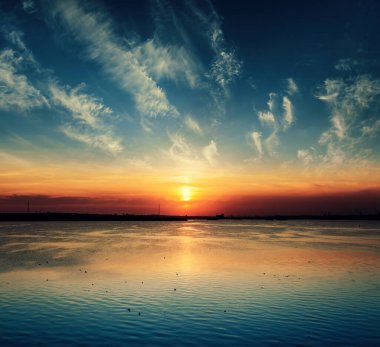 Düşük turuncu gün batımı dramatik bulutlar üzerinde nehir