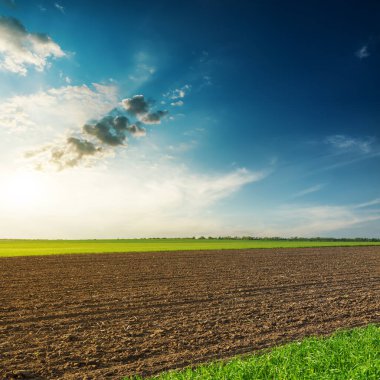 Siyah tarlalar ve bulutlarda gün batımı