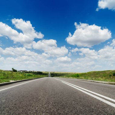 Ufka giden asfalt yol ve beyaz bulutlu derin mavi gökyüzü