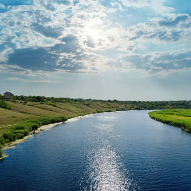 Güneş çarpıcı gökyüzünde ve nehirde yansımalarla