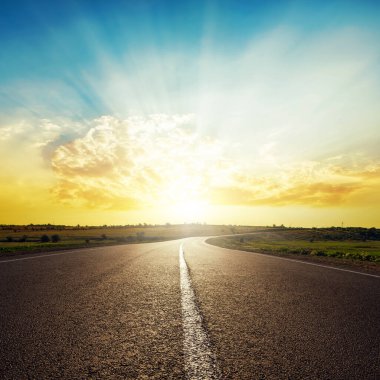 Ufukta asfalt yol ve bulutlarda gün batımı