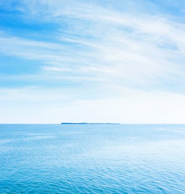 Mavi deniz suyu ve gökyüzünde beyaz bulutlar